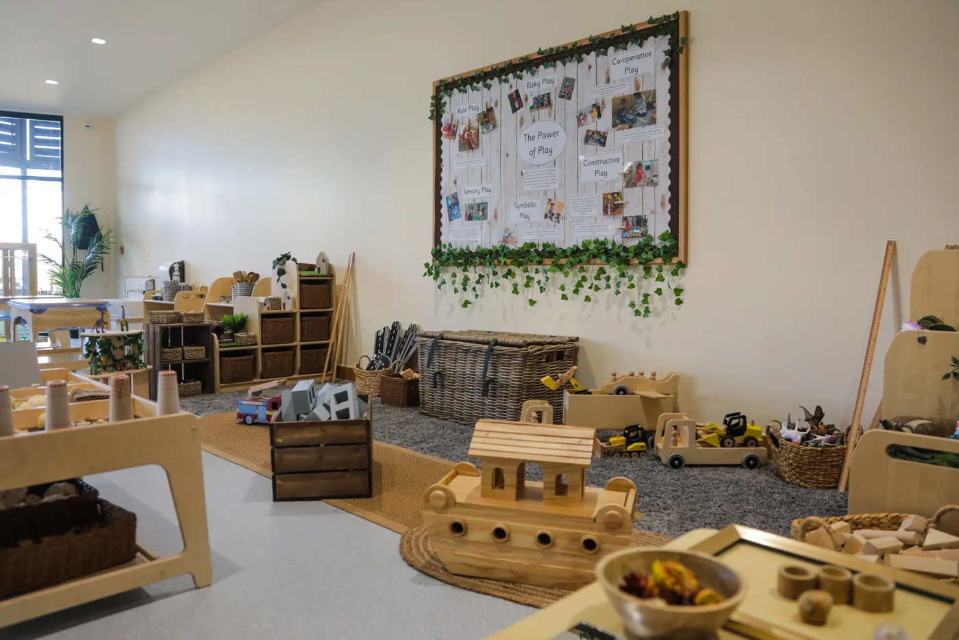 A nursery room at Kids Planet Stanley Square with wooden play furniture, toys and a display board