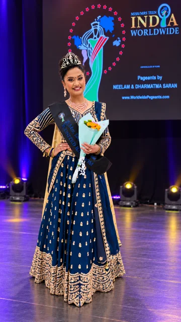 Dr Sivasankari Babu with her crown, sash and flowers on the Mrs India Worldwide stage