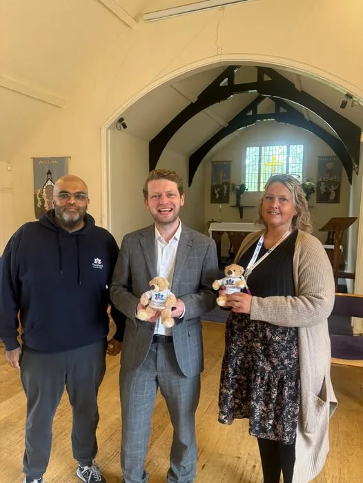 Three people standing inside St Luke's Church in Bowdon, two of them holding small teddy bears in Radfield tops