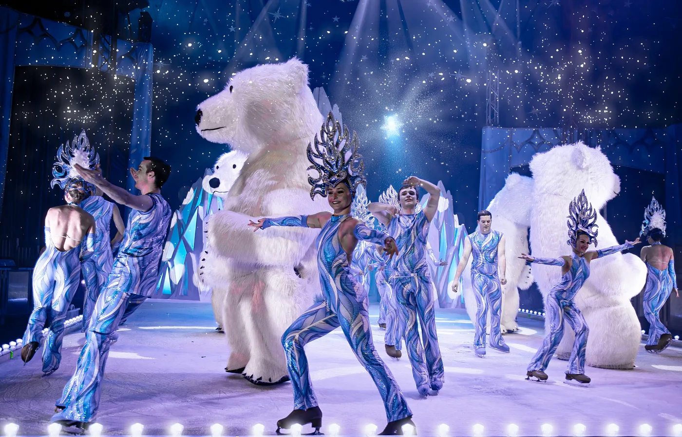 Skaters in blue costumes and ice headdresses with two giant polar bear characters
